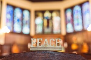 "Peace"-Schriftzug vor sakralen Fenstern
